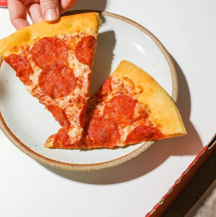 Hand picking up a slice of pepperoni pizza