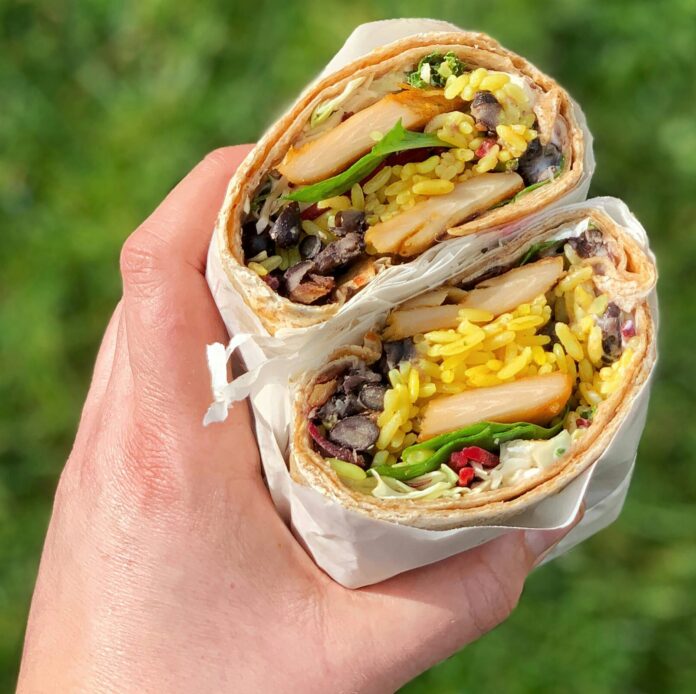 Hand holding chicken burrito