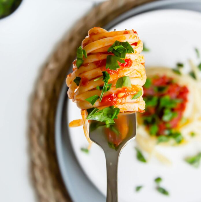 Close-up of Pasta with Tomato Sauce and Herbs on a Fork